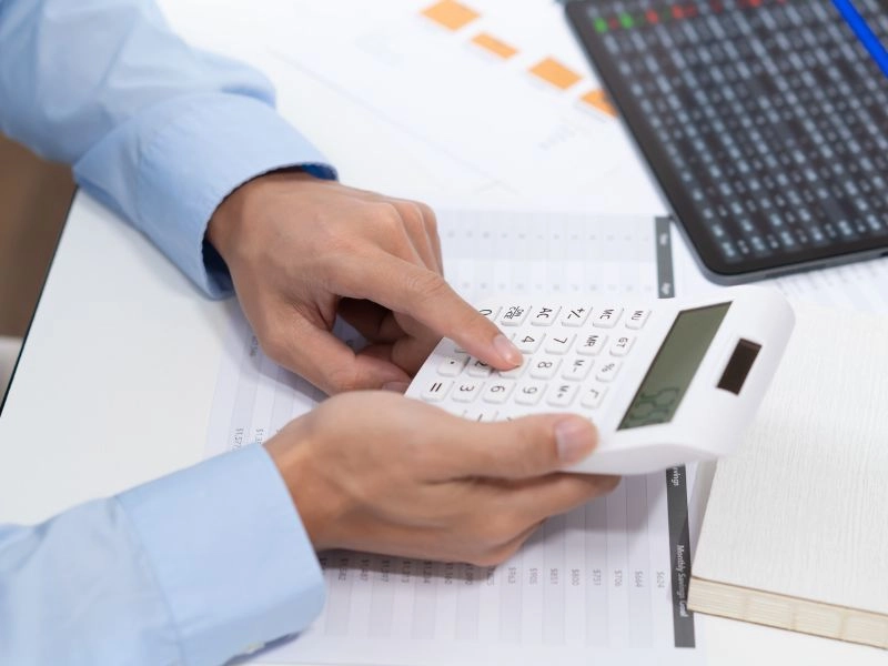Male CPA uses a calculator to prepare a small business profit and loss statement in Raleigh.