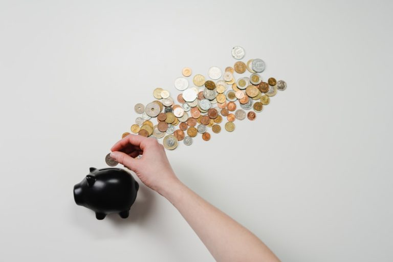 Picture of a person putting coins into a piggy bank wondering do I need a business bank account?