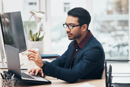 A man with glasses sits at a desk and reviews the business bank account requirements