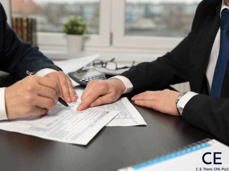 Two men review a tax form and discuss the average cost of tax preparation by a CPA.