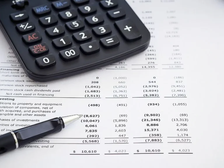A financial statement, pen, and calculator to depict combined vs consolidated financial statements