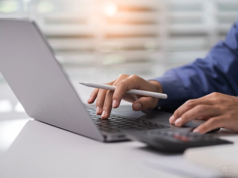 Man typing on latop, exploring the pros and cons of filing a tax extension. 